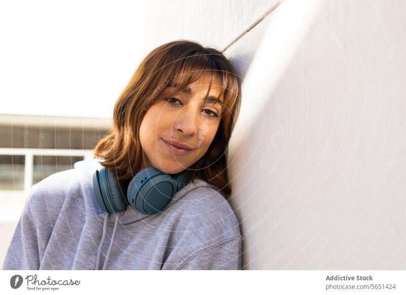 Lässige Frau mit Kopfhörern genießt die Sonne Sonnenlicht Lächeln lässig Erholung jung Lehnen Wand sanft Gesicht im Freien Freizeit Lifestyle urban Großstadt
