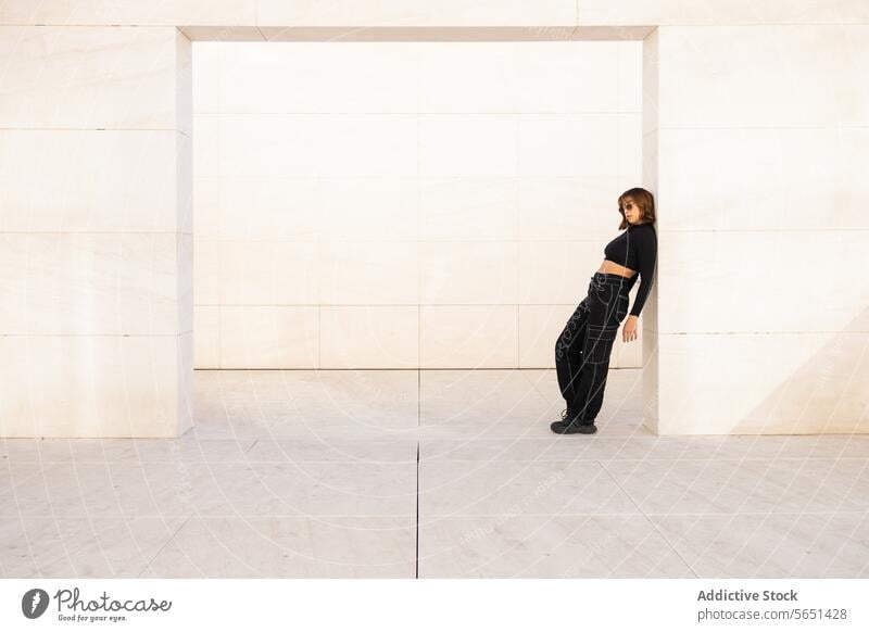 Moderne Frau posiert vor einem minimalistischen Architekturhintergrund modern posierend Struktur Zeitgenosse urban Schwingung Stil selbstbewusst jung Kleidung