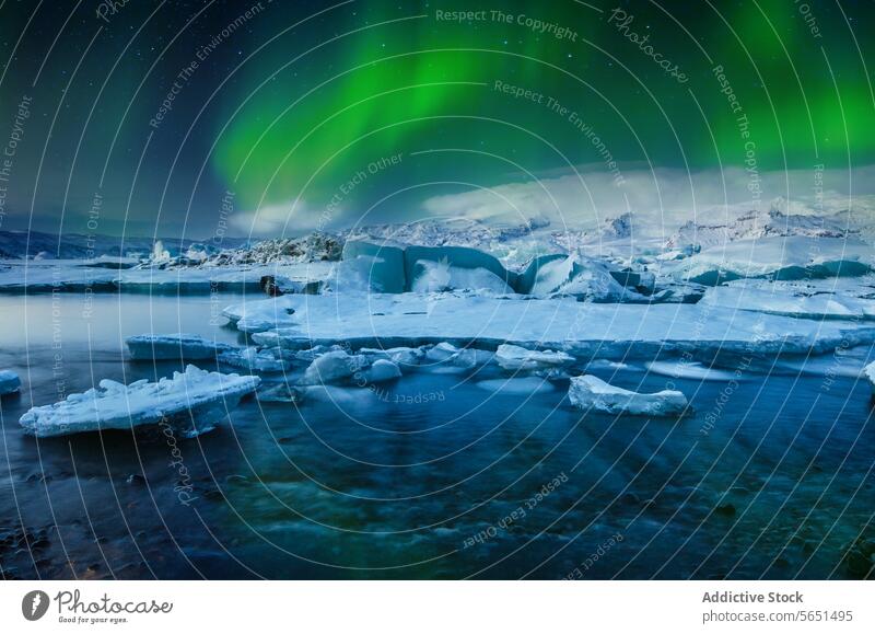 Nordlichter tanzen über einer Gletscherlagune mit Eisbergen und schneebedeckten Bergen in Island Aurora Berge u. Gebirge Schnee Nacht Himmel grün Licht