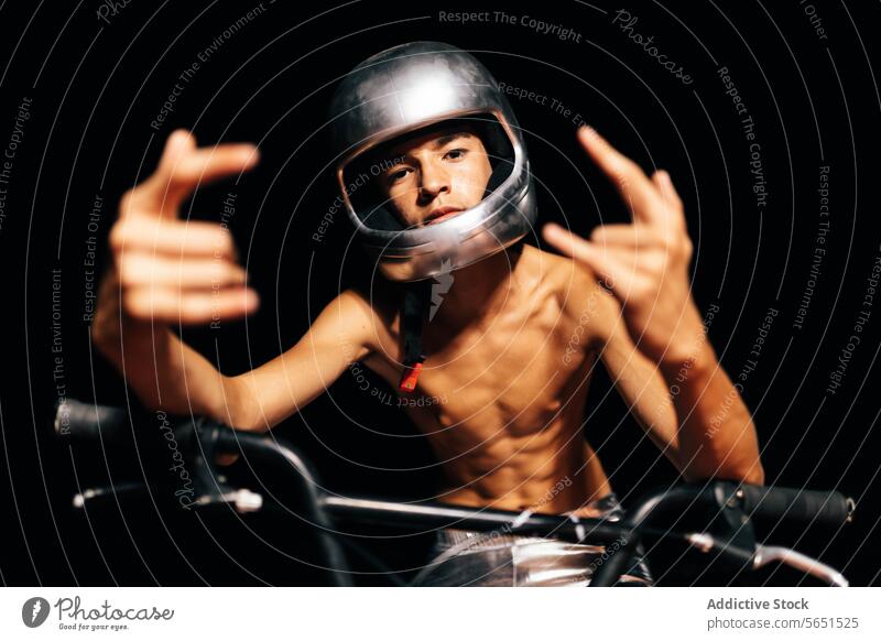 Unerkennbarer junger Mann ohne Hemd, der auf einem Fahrrad mit Lichtern sitzt und eine Geste mit Teufelshörnern zeigt Stuntman Schutzhelm Radfahrer Lenker
