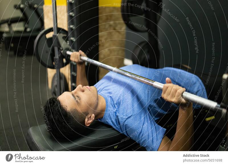 Fitnessbegeisterter junger Mann beim Bankdrücken im Fitnessstudio Training Übung Curl-Hantel Heben Gesundheit Sport Stärke Athlet Fokus Tatkraft Gerät