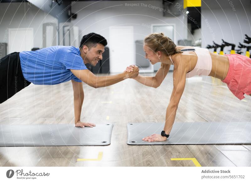 Fitness-Duo in Plank-Position mit motivierendem Faustschlag Schiffsplanken Herausforderung Fitnessstudio Übung Training Stärke Gesundheit Lifestyle Motivation