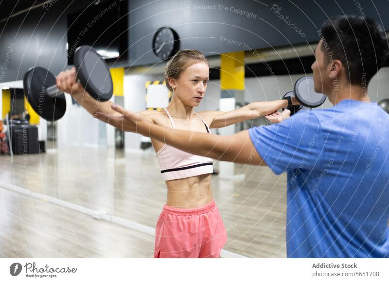 Persönliche Trainingseinheit in einem Fitnessstudio Personal Trainerin Übung Kurzhantel Frau männlich Unterstützung Sport Gesundheit sportlich Stärke muskulös
