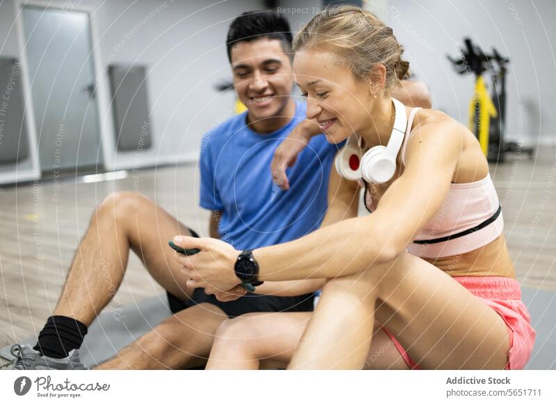 Fitnesspartner ruhen sich aus und lachen gemeinsam im Fitnessstudio Training Partner Mann Frau Lachen Teilen Sitzen Stock Übung Gesellschaft aktiv Lifestyle