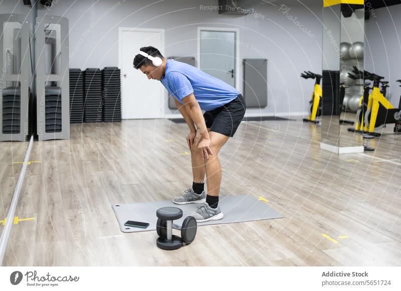 Mann ruht sich nach dem Training in einem modernen Fitnessstudio aus aussruhen Übung Müdigkeit Atem fangen Post-Workout Zeitgenosse Gesundheit