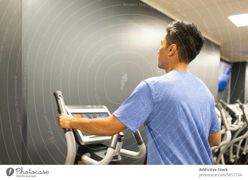 Mann bereitet sich auf ein Training auf einem Laufband in einem Fitnessstudio vor Übung Vorbereitung ruhend blau T-Shirt Seitenansicht Gesundheit Wellness