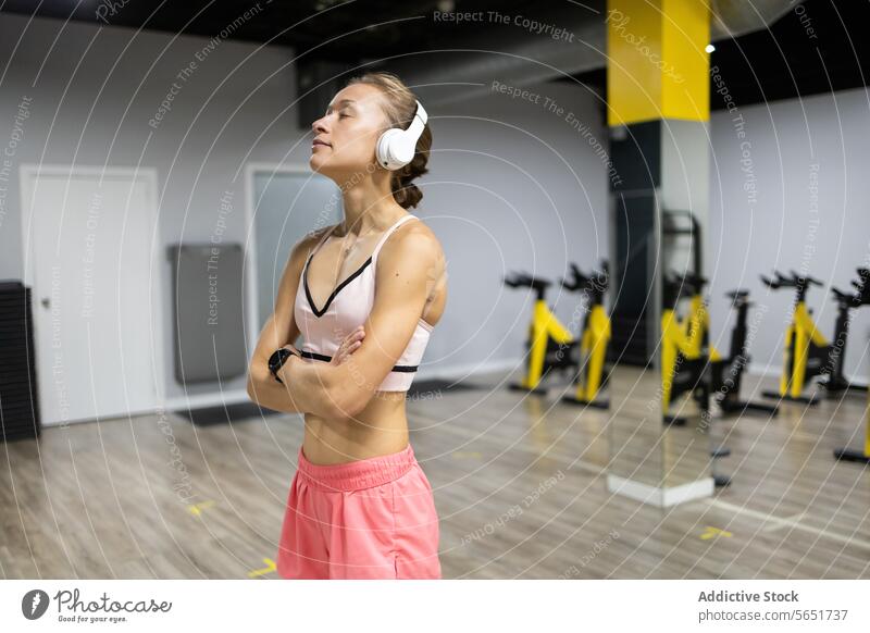 Fitness-Enthusiast macht eine Pause mit Kopfhörern in einem modernen Fitnessstudio Frau Training reflektierend Übung Gesundheit Sport-BH sportliche Freizeit