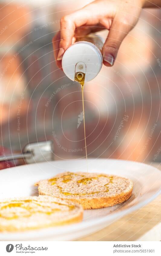 Honig auf eine Scheibe Vollkorntoast träufeln Liebling Nieselregen Zuprosten Frühstück eingießen Hand Glas golden frisch Teller weiß Brot Nahaufnahme