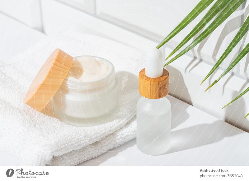 Natürliche Hautpflegeprodukte auf einem hellen Badezimmertisch natürlich organisch Sahne Serum Flasche Glas Arbeitsplatte Handfläche Blatt Handtuch weiß