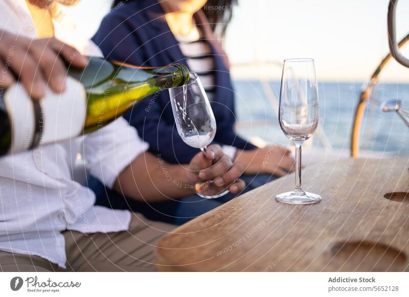 Crop-Paar gießt Champagner in Weingläser auf einer Jacht eingießen Weinglas Alkohol Segelboot Termin & Datum MEER romantisch Liebe Partnerschaft Tisch trinken