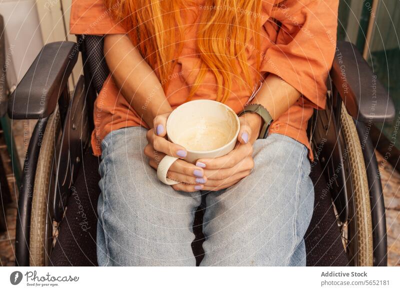 Person im Rollstuhl hält eine Kaffeetasse orangefarbenes Haar Freizeitkleidung sitzend Behinderung Erholung Getränk Beteiligung Becher Zugänglichkeit Jeansstoff