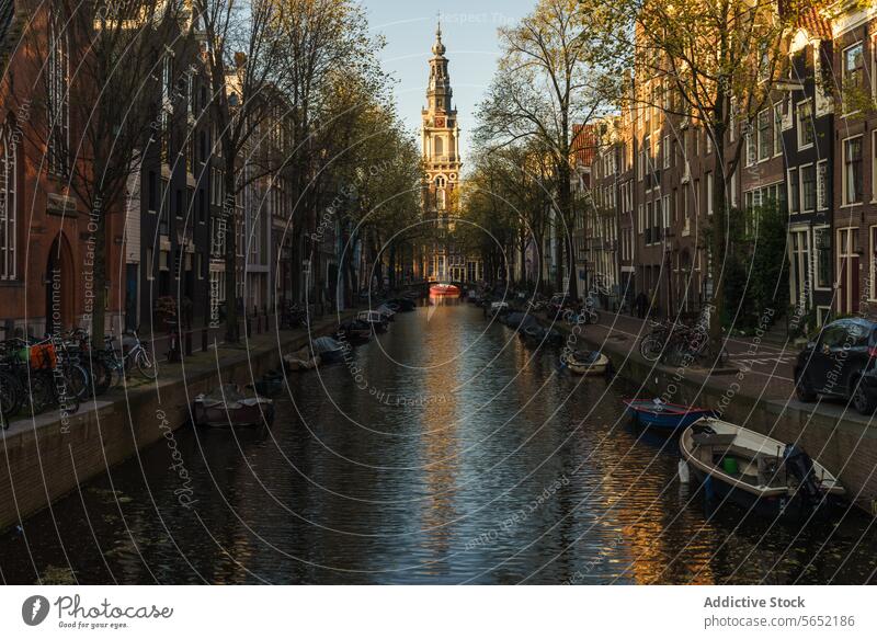 Warmes Sonnenuntergangslicht auf dem Amsterdamer Kanal mit vertäuten Booten und traditionellen niederländischen Häusern Niederländische Häuser Niederlande