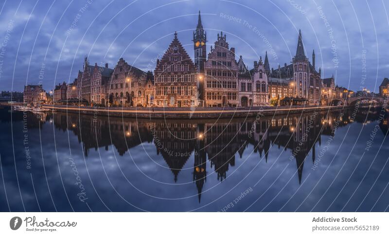 Die historischen Gebäude von Gent spiegeln sich in der Dämmerung im ruhigen Wasser und zeigen den mittelalterlichen Charme der Stadt Historische Bauten