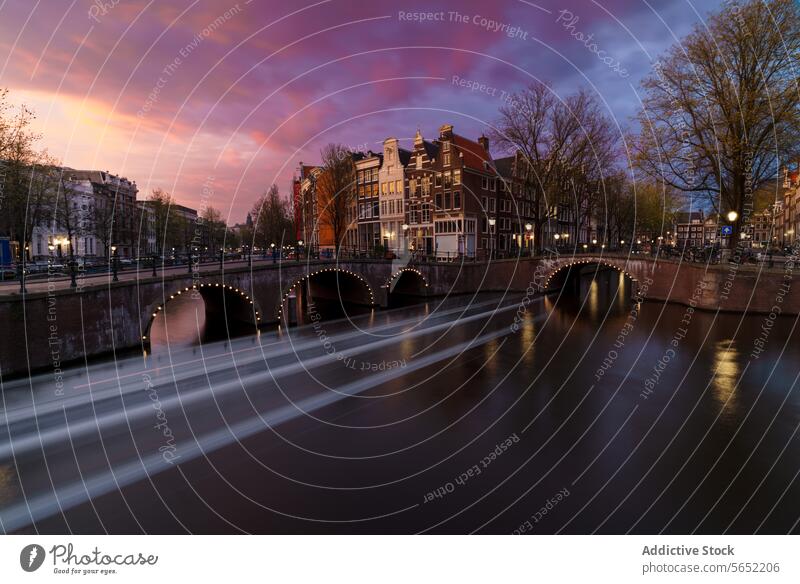 Dämmerungstöne über Amsterdams Grachten mit historischen Brücken und Häusern unter einem leuchtenden Sonnenuntergangshimmel Kanäle Himmel Niederlande Wasser
