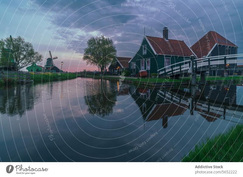 Eine ruhige Abendszene mit typisch holländischen Häusern und einer Windmühle, die sich in den ruhigen Gewässern der Zaanse Schans spiegelt
