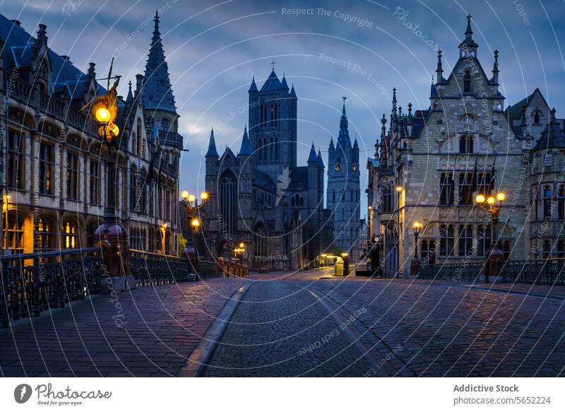 Historische Gebäude und Straßenbeleuchtung in der Morgendämmerung in Gent mit der St.-Bavo-Kathedrale im Hintergrund historische Gebäude Straßenlaternen