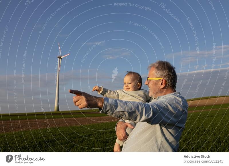 Glücklicher Großvater zeigt einem süßen kleinen Jungen im Windpark etwas Enkel Windmühle Zeigen Finger zeigend Natur Lächeln niedlich Zusammensein Liebe