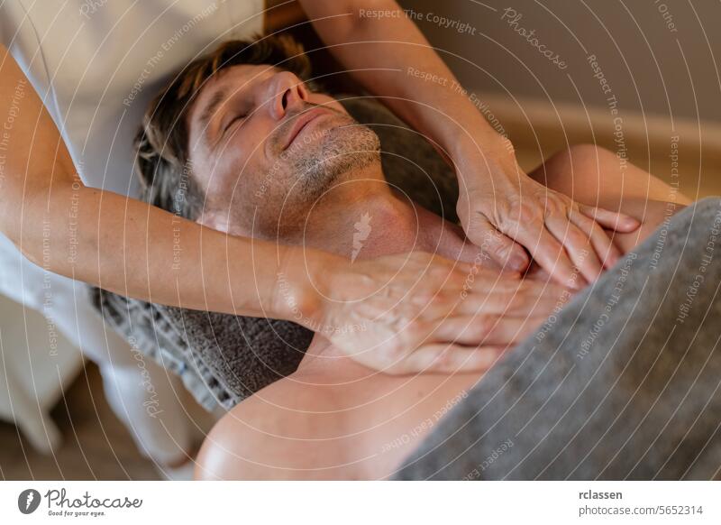 Mann entspannt sich bei einer Brustmassage in einem Spa mit heiterem Gesichtsausdruck. Wellness Hotel Konzept Bild. Massageöle Nackenmassage Erholung