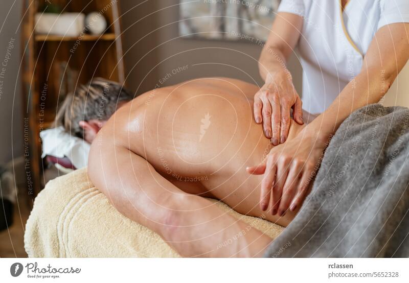 Massagetherapeutin bei der Rückenmassage eines männlichen Kunden im Spa. Wellness Hotel Konzept Bild Mann Resort Massageöle Physiotherapeutin Klinik asiatisch
