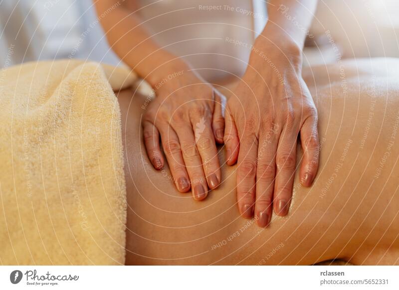 Nahaufnahme von Händen, die eine Rückenmassage an einem mit einem Handtuch bedeckten Kunden durchführen. Schönheitssalon Wellness Hotel Konzeptbild Erholung
