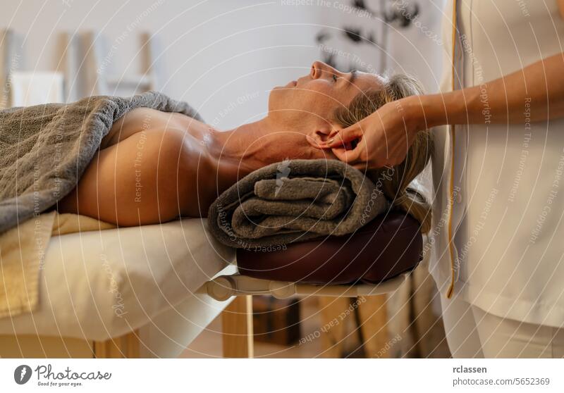Seitenansicht eines Massagetherapeuten bei der Ohrmassage einer entspannten Kundin Hotel asiatisch Schönheitssalon Kopf Frau Erholung Therapeutenhände