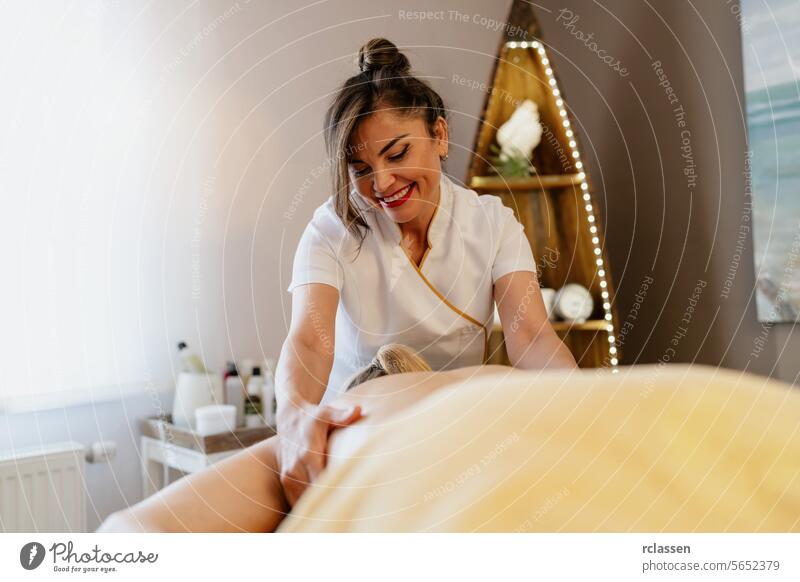 Fröhliche asiatische Masseurin bei der Rückenmassage in einem gemütlichen Spa-Schönheitssalon Wellness Hotel Therapeut Erholung Freude Lächeln Therapie Frau