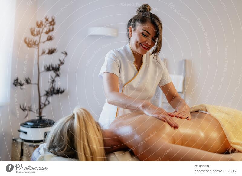 Lächelnde asiatische Masseurin bei der Rückenmassage eines entspannten Kunden in einem Spa-Hotel-Resort Massageöle Physiotherapeutin Schönheitssalon Therapeut