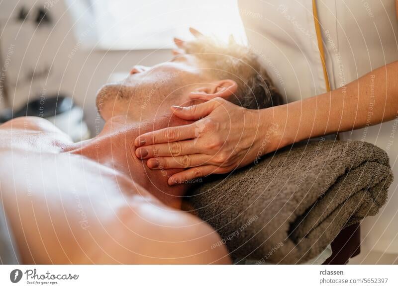 Mann erhält Nackenmassage vom Therapeuten im Wellness-Hotel Physiotherapeutin Massageöle asiatisch Erholung Therapeutenhände Stressabbau Luxus-Spa verwöhnend