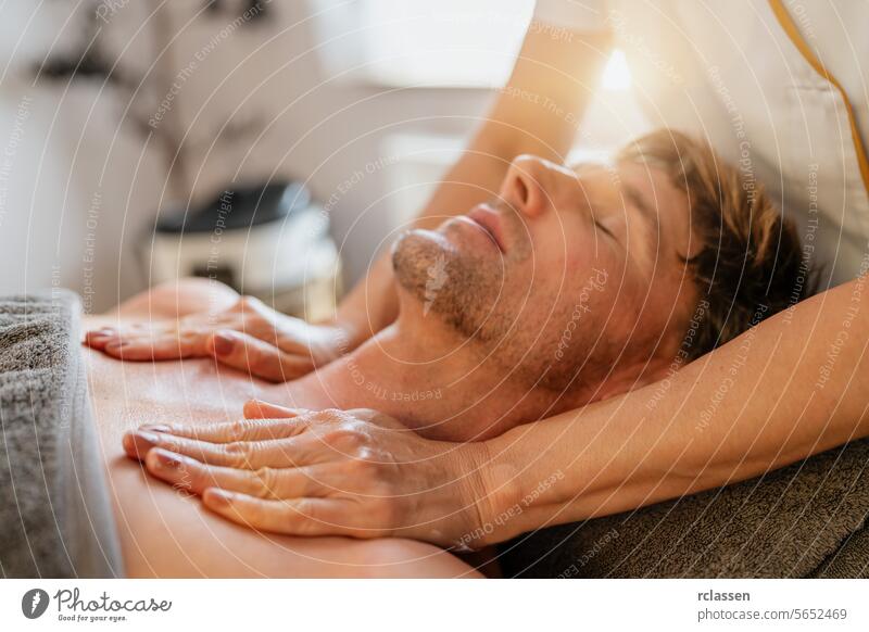 Ein Mann entspannt sich bei einer Brustmassage in einem Spa mit einem ruhigen Gesichtsausdruck. Wellness Hotel Konzept Bild asiatisch Massageöle