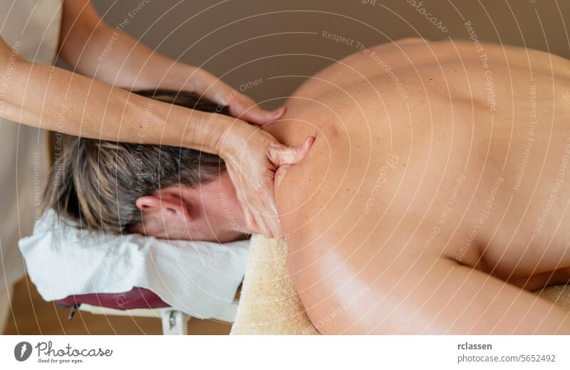 Therapeut bei der Nackenmassage eines männlichen Kunden in einer ruhigen Spa-Umgebung. Wellness Hotel Konzept Bild Resort Massageöle Physiotherapeutin asiatisch