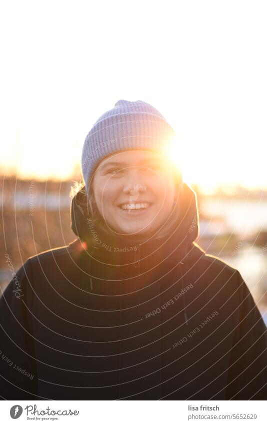 VON DER SONNE GEKÜSST Frau 18-30 Jahre Mütze Winter modern lachen Freude glücklich Warmes Licht Sonnenlicht Sonnenstrahlen Erwachsene Außenaufnahme Farbfoto