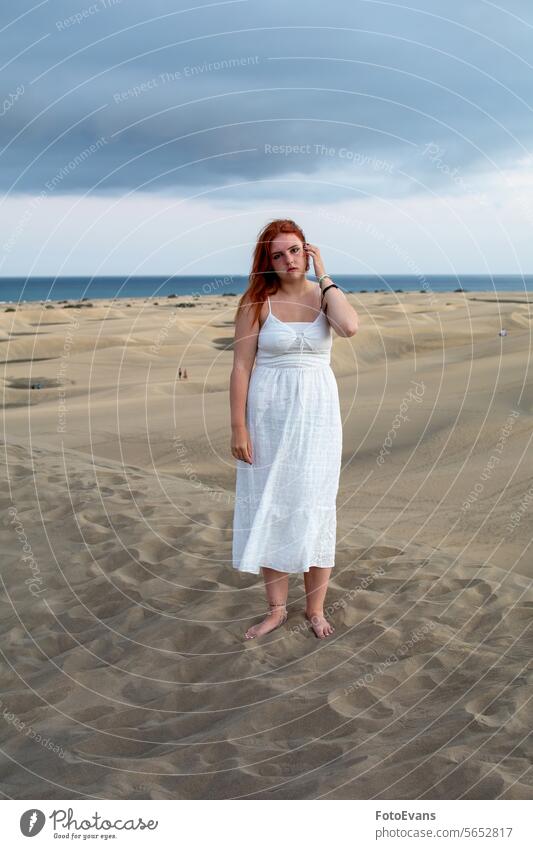Junge Frau steht in den Sanddünen Porträt Tribüne niedlich Kleid Europäer jung Schönheit attraktiv Düne Strand Sandstrand im Freien Sommerzeit weiß Teenager