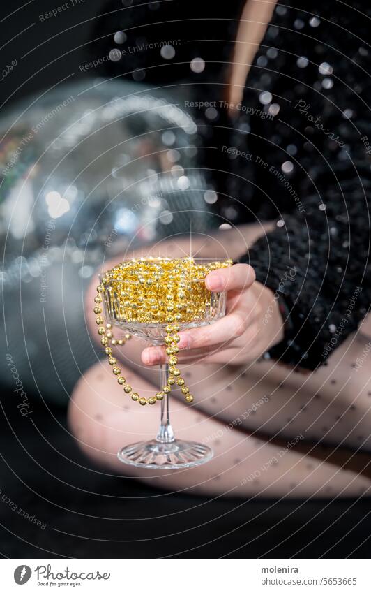 Sektglas voll mit Weihnachtskugeln als alkoholfreies Getränk Champagne Glas Mocktail trinken Party Feier Hand Person schimmernd Discokugel sprudelnd gelb