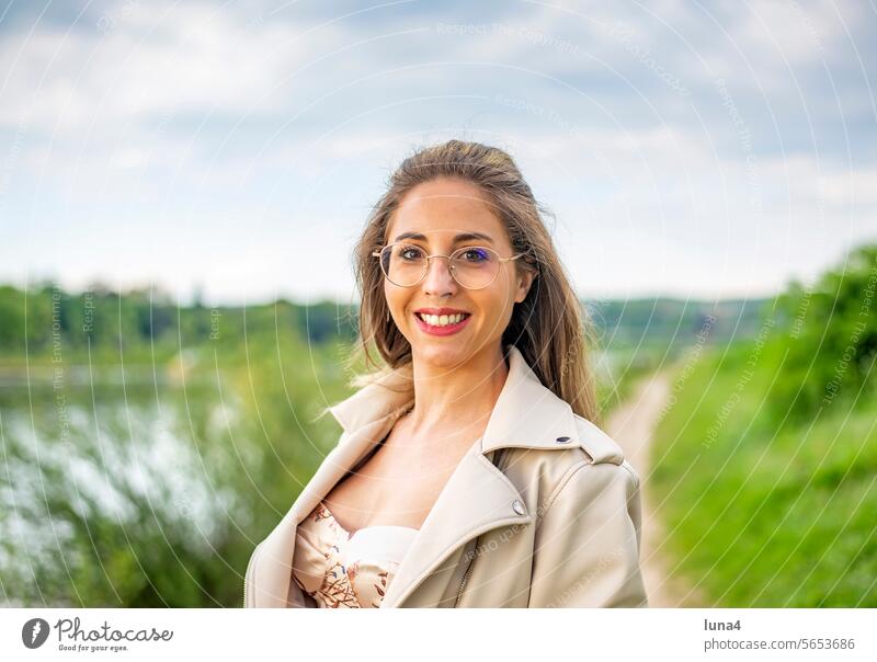 glückliche junge Frau mit Brille steht auf einer Wiese frau lachen hübsch single fröhlich porträt attraktiv optimistisch entspannt freude selbstbewusst
