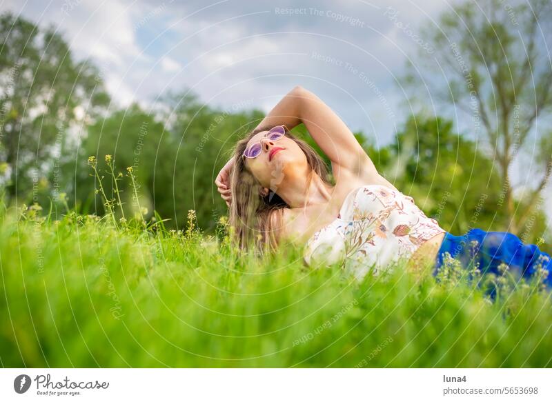 glückliche junge Frau mit Brille liegt auf einer Wiese frau hübsch sinnlich sonnen anmutig single fröhlich porträt attraktiv optimistisch entspannt freude