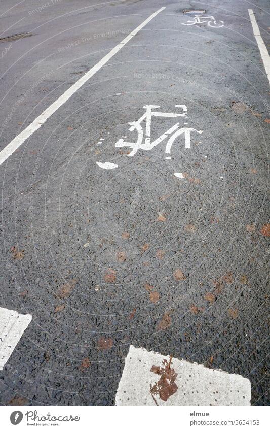 markierter Radweg auf grauem Asphalt mit zwei sich langsam auflösenden Rad - Piktogrammen Fahr Rad Fahrrad Asphaltstraße Fahrbahnmarkierung Fahrradweg Blog StVO