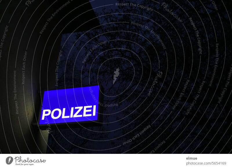 blaues Lichtschild mit POLIZEI an einer Hauswand im Dunkeln Polizei Schild Reklameschild Sicherheit Polizeidienststelle Wache Polizeiwache Leuchtkasten nachts