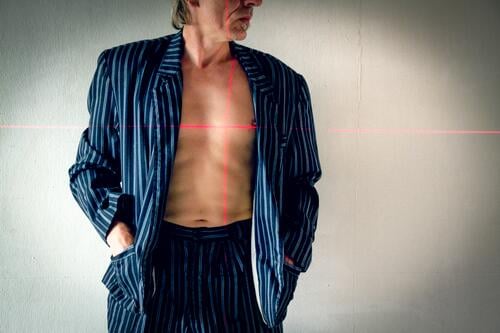 Mann mit Anzug und nackter Brust im Visier eines Lasers nackte Brust Wegsehen laserkreuz anvisiert Herz Im Visier Nackte Haut Oberkörper maskulin schlank