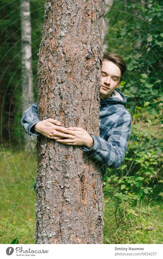 Jugendlicher umarmt Kiefer in einem Wald Aktivist Junge offen Pflege Konzept verbinden Erhaltung Ökologie Umarmen Umwelt Umweltschützer Augen geschlossen