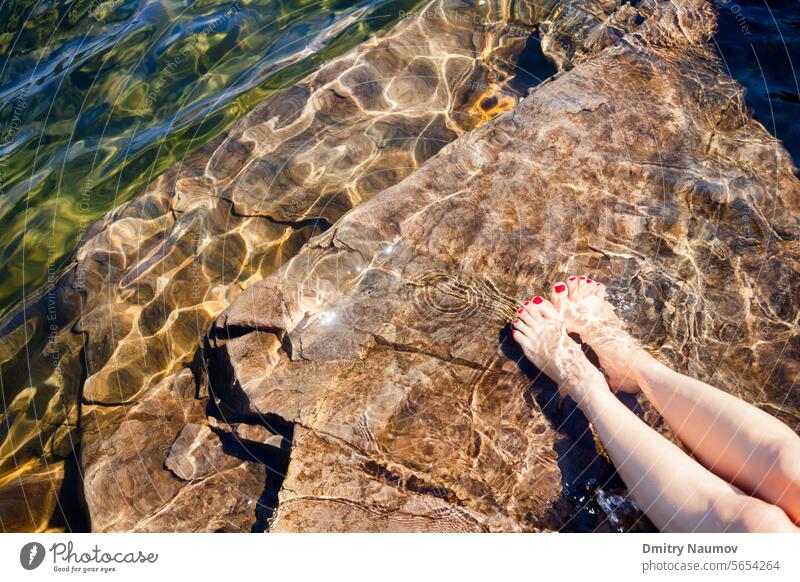 Frau taucht ihre Füße in das kristallklare Wasser eines Sees in Norwegen Erwachsener unverhüllt Barfuß Strand Sauberkeit übersichtlich cool Kristalle Dip