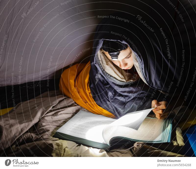 Junge liest ein Buch mit Taschenlampe bei Nacht Schlafsack Bett Schlafenszeit Windstille Lager Camping Kind Kindheit Konzentration dunkel Dunkelheit träumen