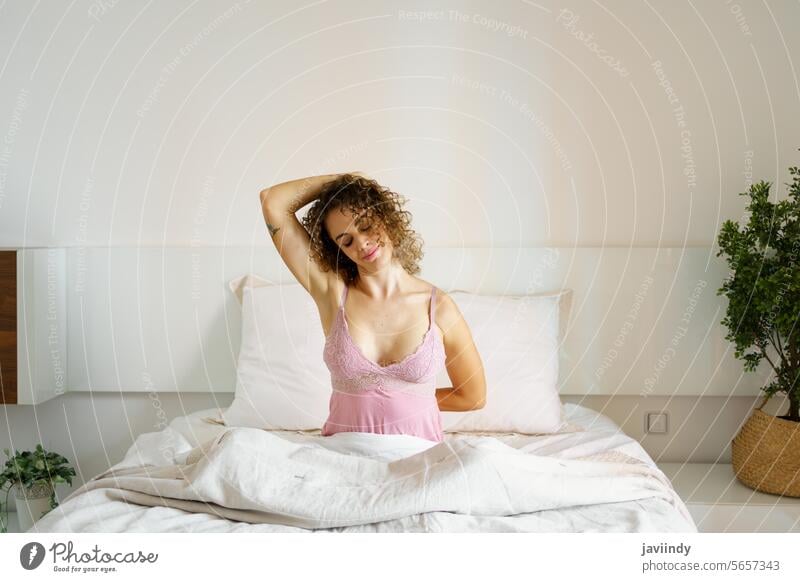 Glückliche Frau macht Dehnungsübungen auf dem Bett Morgen wach Lächeln Augen geschlossen Übung Nachtwäsche gemütlich Schlafzimmer Erwachsener froh Komfort