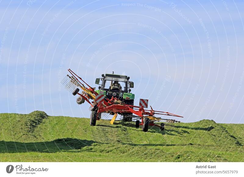 Heuernte mit einem Traktor auf einem Feld im Oberallgäu traktor mähen landwirt bauer heuernte gras feld landwirtschaft mähwerk fahrzeug industrie arbeit fahren