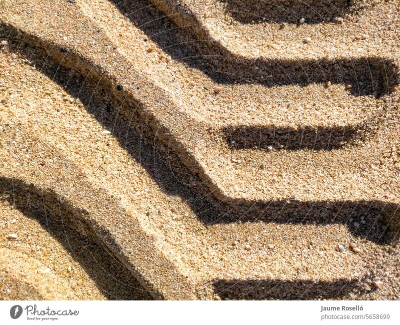 Hintergrund der Traktorräder mit seltsamen Formen und mit Schatten auf dem Strand Sand mit nassen Boden geprägt Lastwagen Verkehr Land Fußspur wüst Transport
