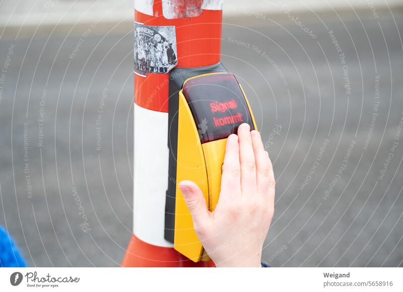 Eine Kinderhand auf einem Ampeldrücker, auf dessen Display "Signal kommt" steht Hand Straße urban Alltag Hinweis Zeichen warten Straßenübergang Wartezeit Dauer