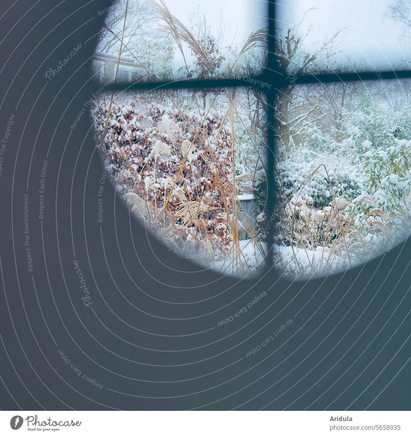 Blick aus einem runden Fenster mit Fensterkreuz auf winterliche Gärten Winter Landschaft Garten Durchblick Haus Schnee