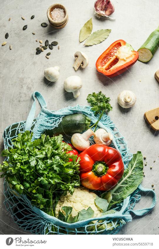 Verschiedene gesunde Bio-Gemüse in blauen Mesh-Lebensmittel Tasche auf dem Küchentisch, Blick von oben. Gesundes Essen Kochen Zutaten verschiedene Gesundheit