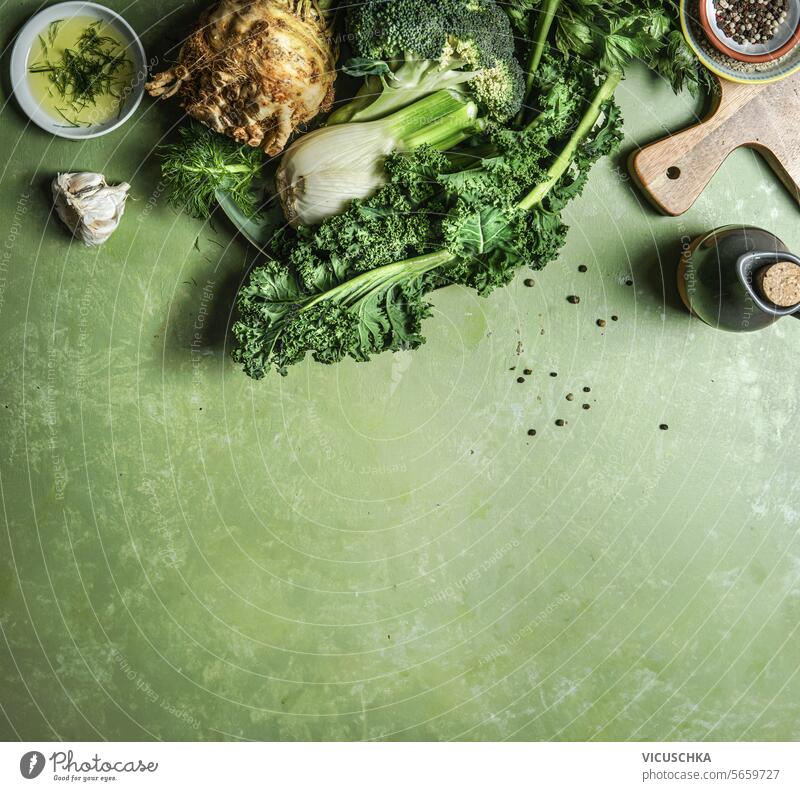 Grünes Gemüse: Brokkoli, Sellerie, Fenchel und Grünkohl auf einem Küchentisch mit Kochzutaten, Draufsicht mit Kopierbereich. Umrandung Entgiftungsnahrung grün