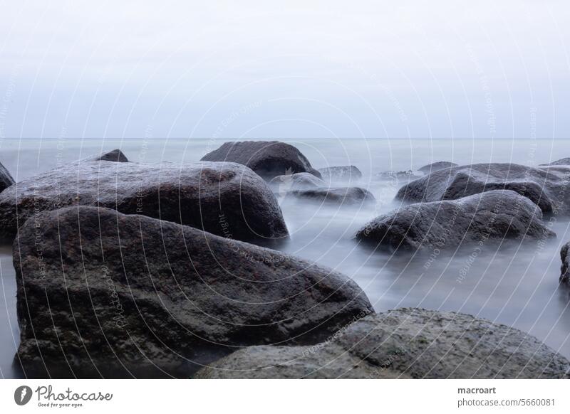 Langzeitbelichtung der Wellenbewegung an einer Steinküste am trüben Abend langzeitbelichtung ostsee steinküste trübes wetter abend wolken wolkenverhangen trist