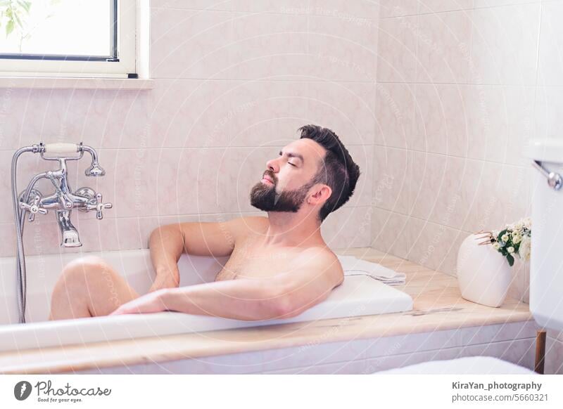 Bärtiger Mann genießen und entspannt im Bad Zeit in beige Vintage Badezimmer. Haut und Selbst-Pflege-Konzept, Männer Gesundheit Konzept. Selbstfürsorge Vollbart